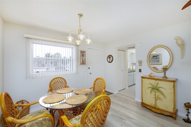 dining space featuring a textured ceiling, light hardwood / wood-style floors, and a notable chandelier