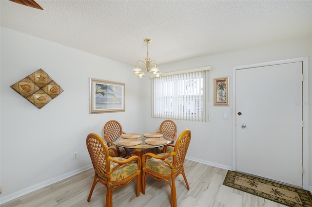 dining area featuring a notable chandelier, a textured ceiling, and light hardwood / wood-style flooring