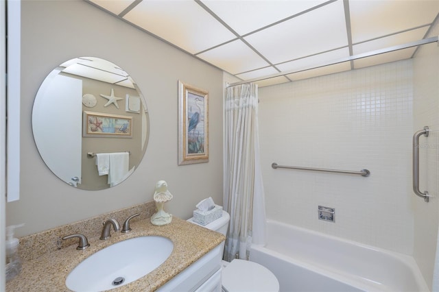 full bathroom with a paneled ceiling, shower / tub combo with curtain, vanity, and toilet