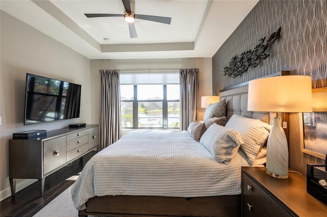 bedroom featuring a raised ceiling, ceiling fan, and dark hardwood / wood-style flooring