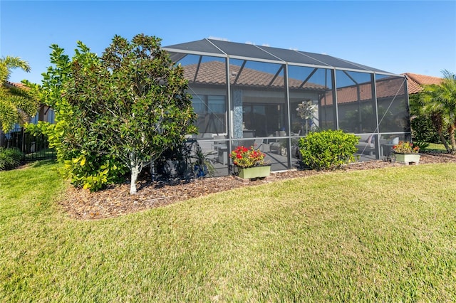 rear view of house featuring glass enclosure and a yard