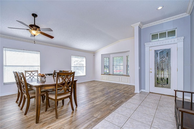 dining room featuring ceiling fan, vaulted ceiling, a textured ceiling, light tile patterned floors, and ornamental molding