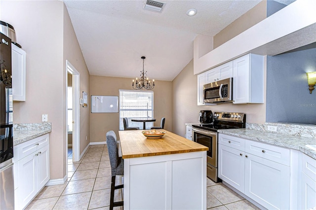 kitchen with wooden counters, stainless steel appliances, white cabinetry, a notable chandelier, and a kitchen island