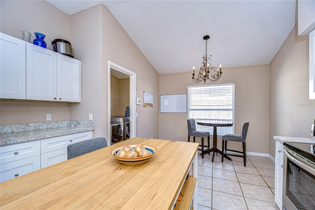 dining room with separate washer and dryer, light tile patterned floors, vaulted ceiling, and an inviting chandelier