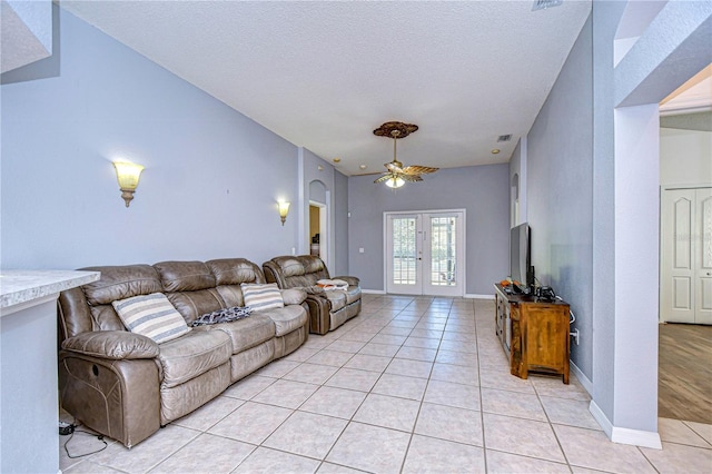 living room featuring light tile patterned floors, french doors, a textured ceiling, and ceiling fan