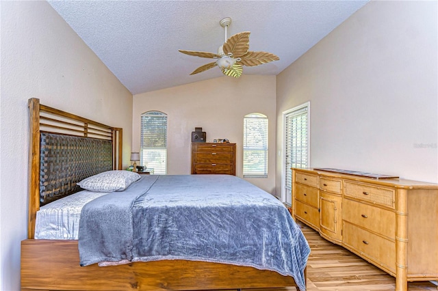 bedroom with vaulted ceiling, ceiling fan, light hardwood / wood-style flooring, and a textured ceiling