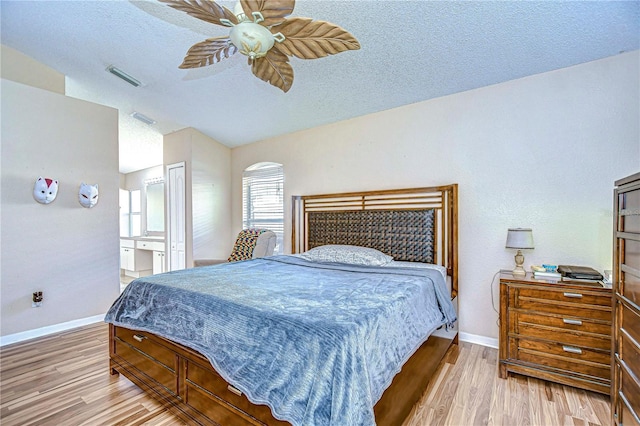 bedroom featuring ensuite bath, ceiling fan, light hardwood / wood-style floors, and a textured ceiling