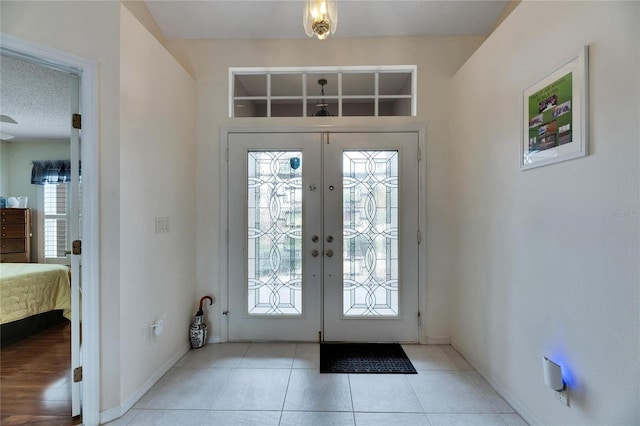 foyer entrance with french doors, plenty of natural light, light tile patterned flooring, and a textured ceiling