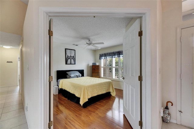 bedroom with ceiling fan, a textured ceiling, and light hardwood / wood-style flooring