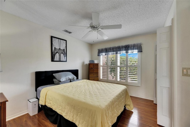 bedroom with a textured ceiling, ceiling fan, and dark hardwood / wood-style flooring