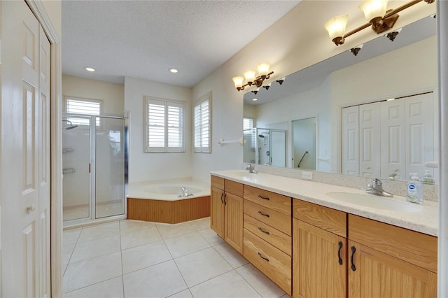 bathroom with a textured ceiling, independent shower and bath, tile patterned flooring, and vanity