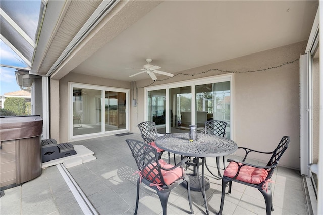 view of patio / terrace with ceiling fan, a hot tub, and glass enclosure