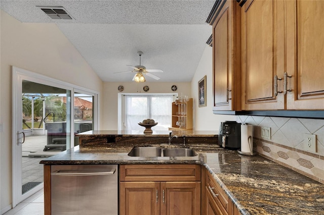 kitchen featuring a textured ceiling, dishwasher, lofted ceiling, tasteful backsplash, and sink