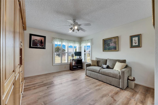 living room with a textured ceiling, ceiling fan, and light hardwood / wood-style floors