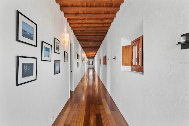 hall featuring dark wood-type flooring, beamed ceiling, and wooden ceiling