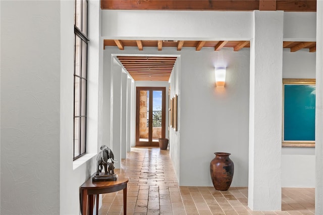 corridor featuring beamed ceiling and french doors