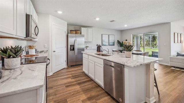 kitchen with white cabinets, sink, stainless steel appliances, and an island with sink