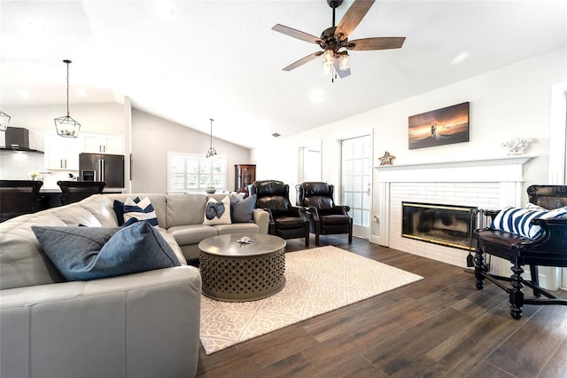 living room featuring lofted ceiling, a brick fireplace, dark hardwood / wood-style floors, and ceiling fan