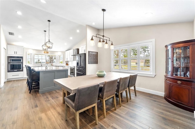 dining room with hardwood / wood-style flooring and vaulted ceiling