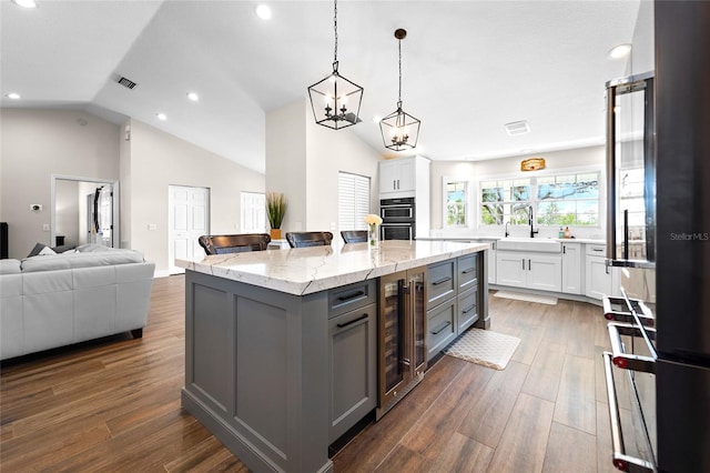 kitchen with wine cooler, gray cabinetry, a kitchen island, and white cabinets