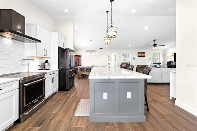 kitchen with white cabinetry, wall chimney exhaust hood, a center island, and electric range