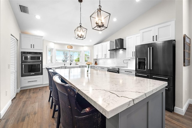 kitchen featuring a center island, high quality fridge, and wall chimney exhaust hood