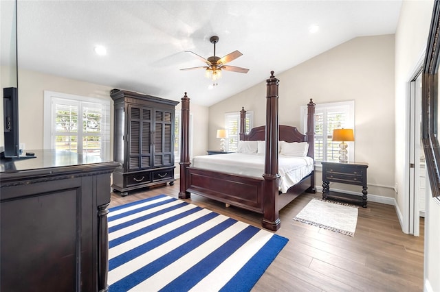 bedroom featuring multiple windows, dark hardwood / wood-style flooring, vaulted ceiling, and ceiling fan