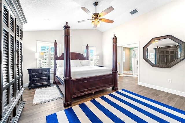 bedroom with lofted ceiling, dark hardwood / wood-style floors, ensuite bathroom, and a textured ceiling