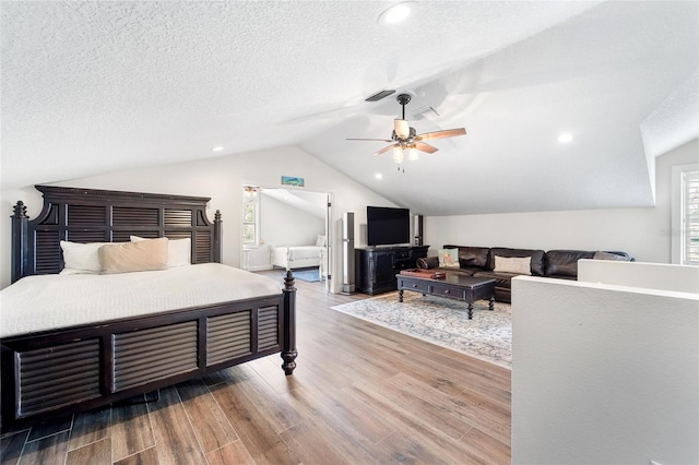 bedroom with lofted ceiling, a textured ceiling, and light wood-type flooring