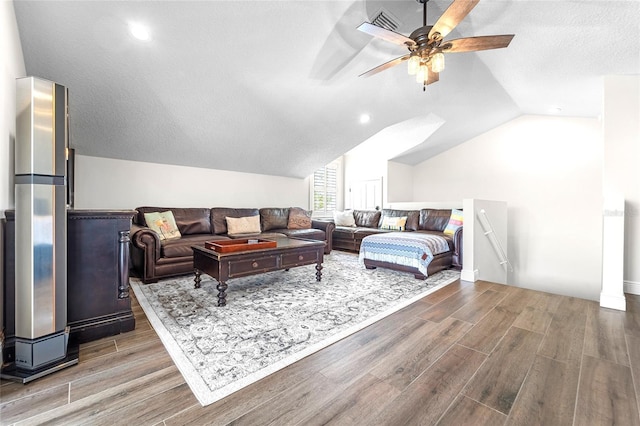 living room featuring ceiling fan, lofted ceiling, hardwood / wood-style floors, and a textured ceiling