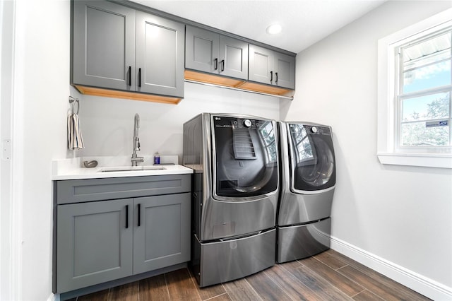 clothes washing area featuring cabinets, sink, dark wood-type flooring, and washer and clothes dryer