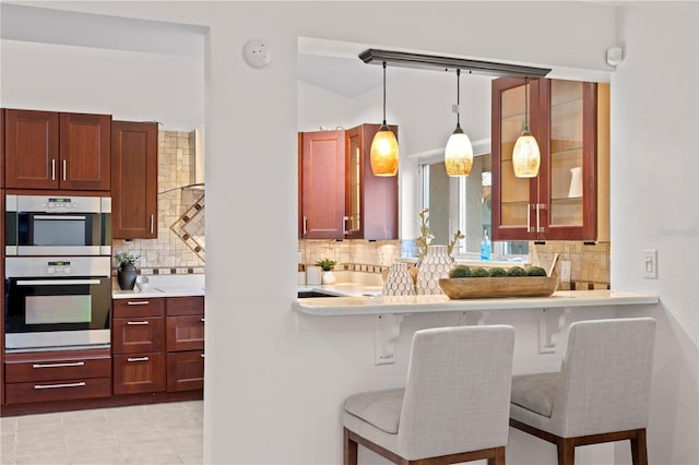 8701 Ballantrae Way, Tampa, FL 33647 - kitchen featuring double oven, a kitchen bar, tasteful backsplash, light tile patterned flooring, and decorative light fixtures