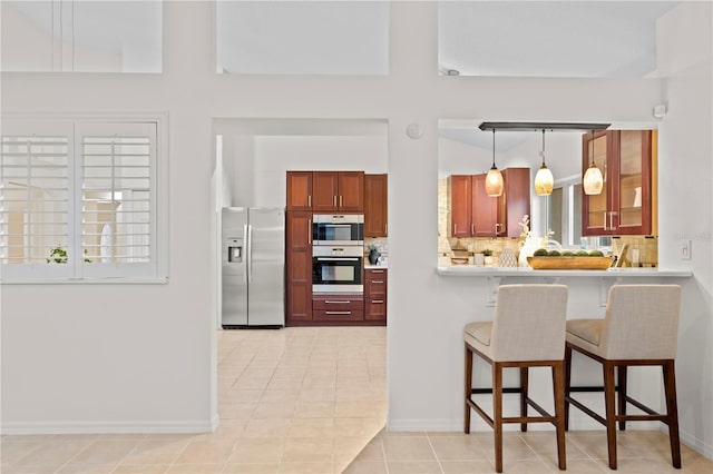 8701 Ballantrae Way, Tampa, FL 33647 - kitchen with pendant lighting, backsplash, stainless steel refrigerator with ice dispenser, a kitchen bar, and light tile patterned flooring