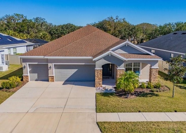 view of front of property with concrete driveway, a front yard, stucco siding, a garage, and stone siding