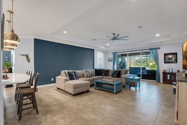 living room featuring ceiling fan and a tray ceiling