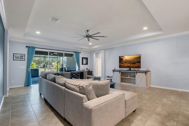 living room with a raised ceiling, crown molding, and ceiling fan