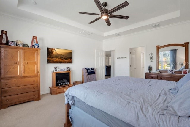 carpeted bedroom with ceiling fan, crown molding, and a tray ceiling