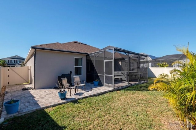 back of house featuring stucco siding, a gate, fence, glass enclosure, and a patio area