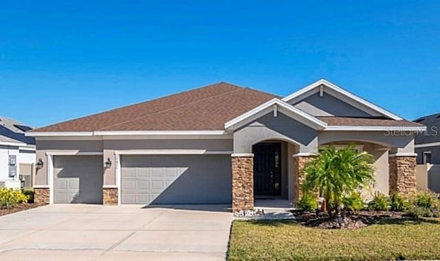 view of front facade featuring a garage, stone siding, driveway, and stucco siding