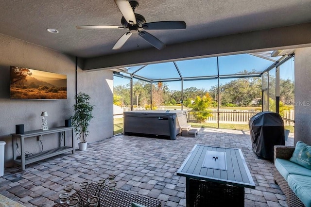 view of patio / terrace featuring a lanai, a ceiling fan, a hot tub, and a grill