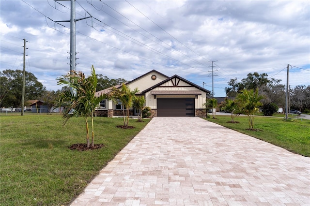 view of front of home with a garage, stone siding, a front lawn, and decorative driveway