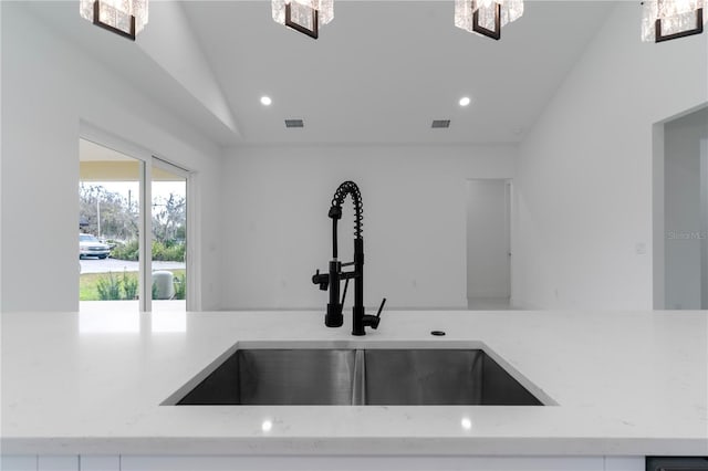 room details featuring light stone counters, recessed lighting, visible vents, and a sink