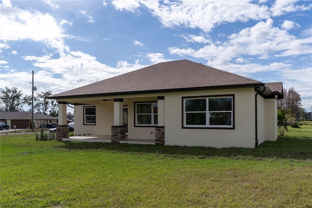 view of front of property featuring roof with shingles, a front yard, and stucco siding