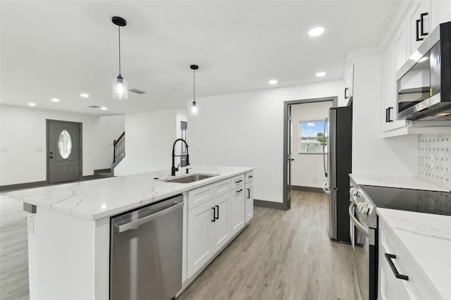 kitchen featuring sink, white cabinetry, hanging light fixtures, stainless steel appliances, and a kitchen island with sink