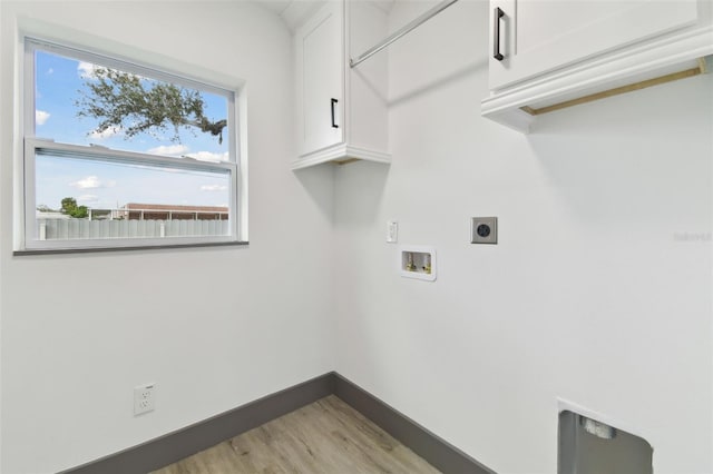 clothes washing area featuring electric dryer hookup, washer hookup, light hardwood / wood-style flooring, and cabinets