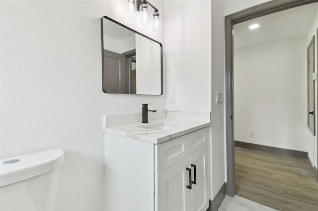 bathroom with hardwood / wood-style flooring, vanity, and toilet