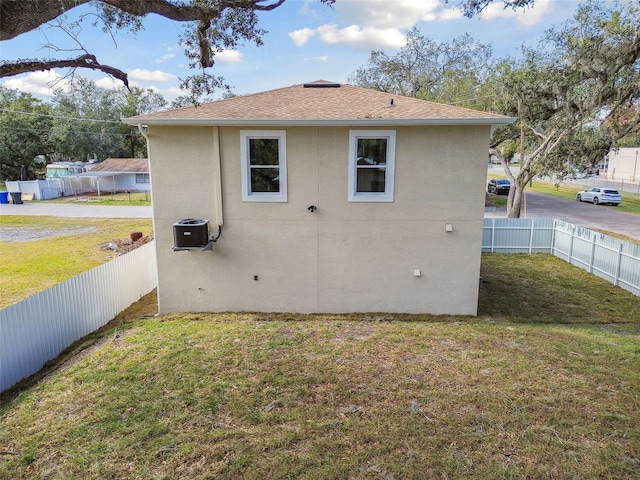 back of house featuring central AC and a lawn