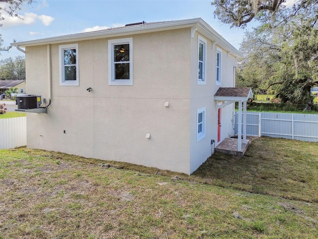 view of side of property with central AC unit and a lawn