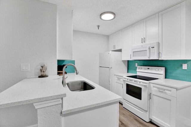 kitchen featuring kitchen peninsula, tasteful backsplash, white appliances, sink, and white cabinets