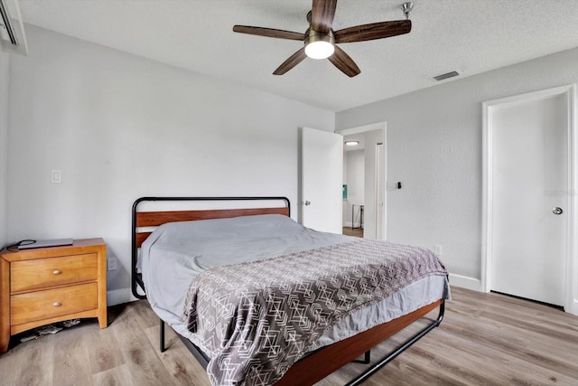 bedroom featuring ceiling fan, a textured ceiling, and light wood-type flooring